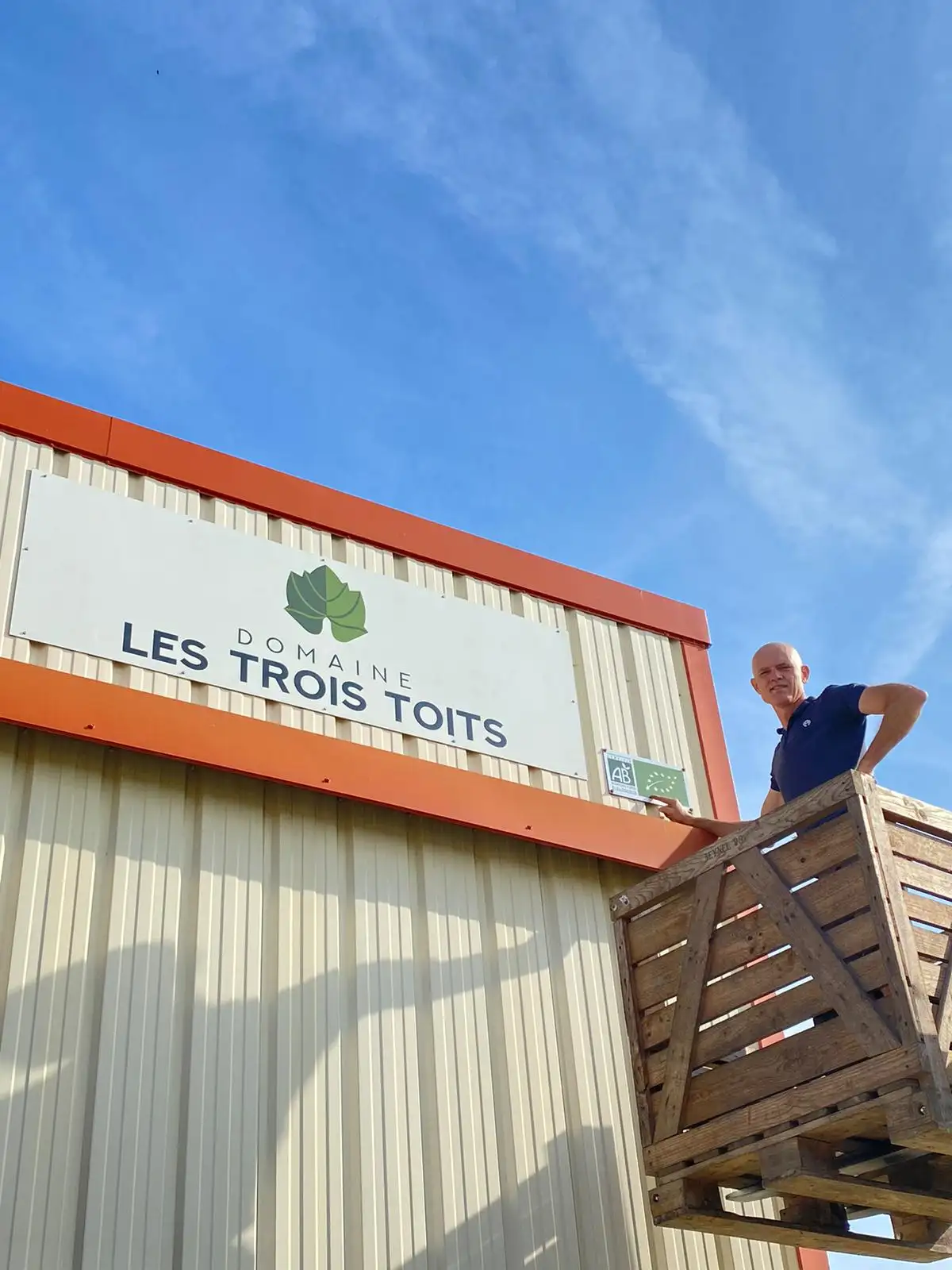 Personne en nacelle et panneau publicitaire pour les trois toits