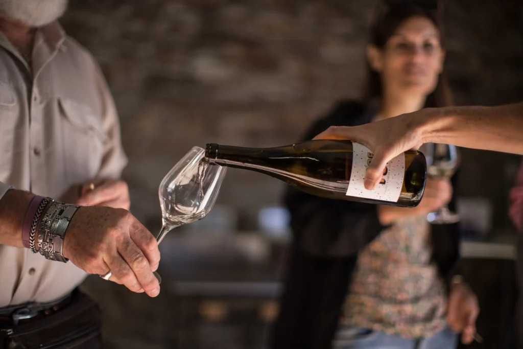 Personne qui sert du vin blanc à une autre personne